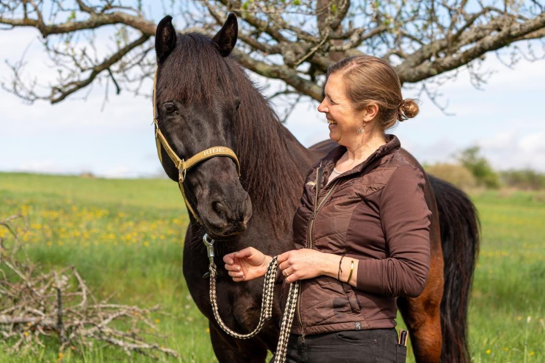 Dr. Rike Wagenhäuser mit ihrem Pferd unter einem blühenden Obstbaum